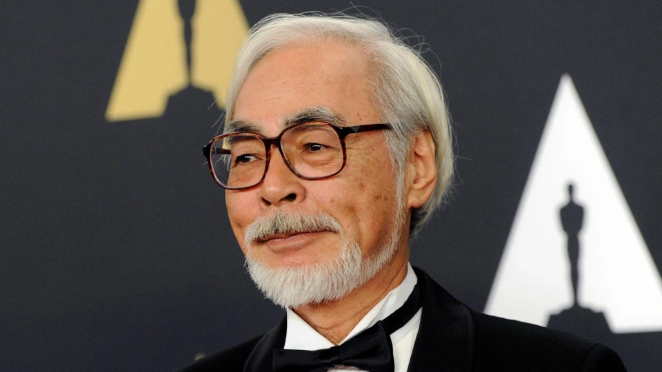 Мужчина с седыми волосами, в очках, с седой бородой и усами, в смокинге, довольно сморит в сторону