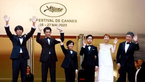 Группа из пяти мужчин в чёрных пиджаках и чёрных брюках, а также женщина в белом платье, радостно машут руками