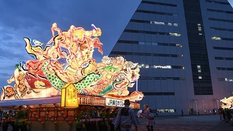 Группа людей тянет большой плот по улице, на плоту установлена подсвеченная фигура