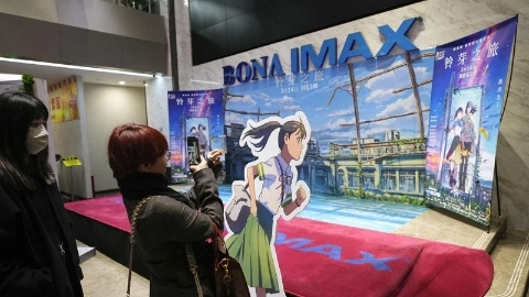 Женщина в куртке снимает на телефон декорации в кинотеатре