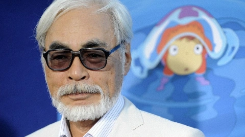 Седой мужчина с бородой, в тёмных очках, в белом пиджаке и белой рубашке, позирует на фоне постера фильма