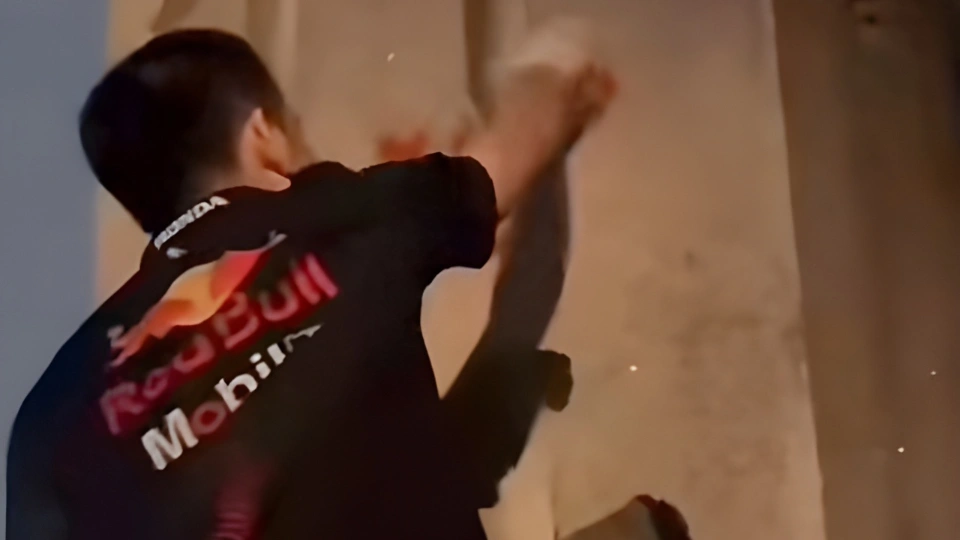 Мужчина с чёрными волосами, в футболке, наносит надпись на стену