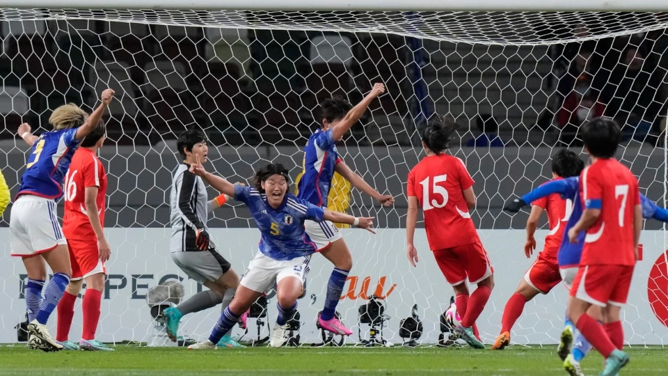 Футболисты в синей форме радуются забитому мячу, футболисты в красном грустно провожают мяч